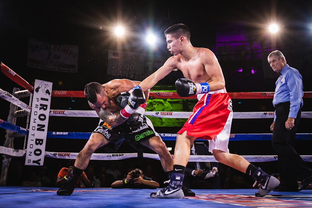 Dynamic scene of athletes in a boxing ring engaged in a fierce match under bright lights.