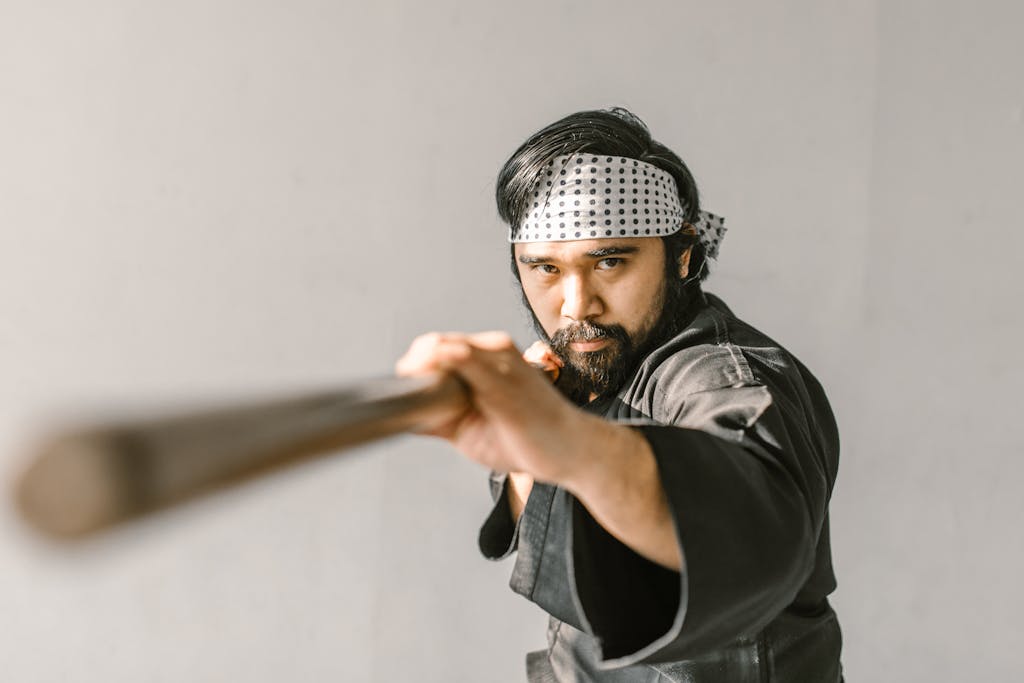 Martial artist focused on wielding a bo staff, showcasing traditional techniques indoors.