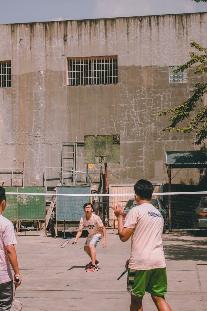 Two teenagers playing an outdoor badminton game with energy and focus.
